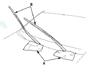 3. Raise the wiper arms (B) off the windshield, then